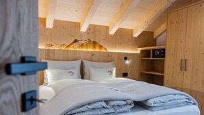 Een slaapkamer met houten lambrisering, een bed, kussens en een wandplank.