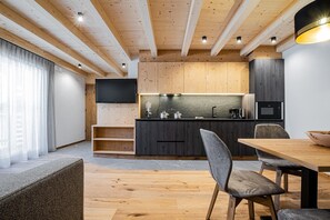 A modern kitchen with wooden cabinetry, a flat-screen TV, and a dining area with a wooden table and chairs.