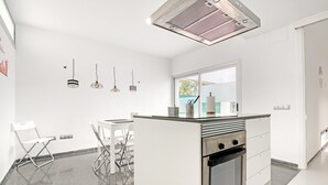 A modern kitchen with white cabinetry, a built-in oven, and a window above the sink.