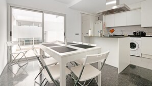 A modern kitchen with white cabinets, a dining table with chairs, and a built-in washing machine.