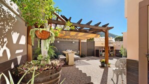 A courtyard with a pergola, outdoor seating, and potted plants. - Vacation Home 'Vitamina Village' with Sea View, Shared Pool, Garden & Wi-Fi (Adeje)