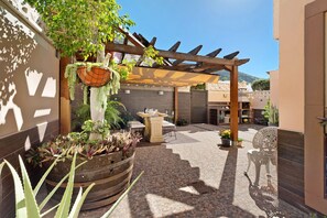 Un cortile con una pergola, posti a sedere all'aperto e piante in vaso.