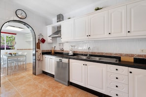 A modern kitchen with white cabinets, a dishwasher, a sink, and a clock on the wall.