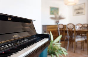 A piano in a room with a dining table and chairs.