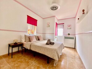 Una camera da letto con un letto, un comodino, una cassettiera e una finestra con tenda rossa.