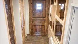 Ein schmaler Flur mit Holzdielen, einer Holztür am Ende und einem weißen Heizkörper auf der rechten Seite.