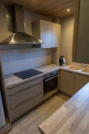 Una cocina moderna con extractor de acero inoxidable, horno empotrado, cafetera y encimeras de madera.