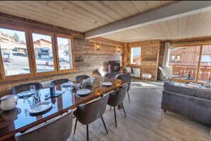 Un interior de madera con una mesa de comedor preparada para cuatro comensales, un sofá y una chimenea.
