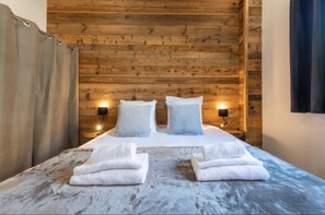 A wooden cabin-style room with a bed, two wall-mounted lights, and a curtain. - Chalet '24 Pers Sur La Roite Du Tour' with Balcony and Wi-Fi (Huez)
