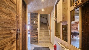 Un couloir en bois avec un mur en pierre, un escalier et un extincteur.