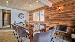 Un espace repas doté d’un plafond en bois, d’une horloge murale ronde et d’une grande fenêtre.