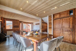 Un interior de madera con una mesa de comedor, sillas y una puerta grande de madera.