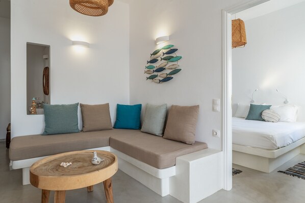 Un salon moderne avec un canapé, une table basse ronde en bois et une décoration murale représentant des poissons.
