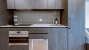 A modern kitchen with wood-paneled cabinets, a stainless steel refrigerator, and a tiled backsplash.