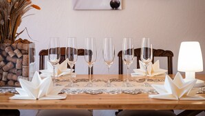 Una mesa de comedor con seis copas de vino, un jarrón con flores secas y un candelabro.