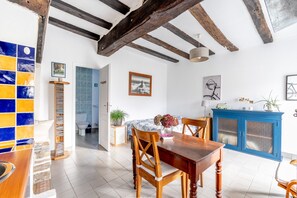 A dining area with a wooden table and chairs, a blue cabinet, and a tiled backsplash.