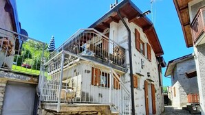 Un edificio de piedra con balcón, una escalera y un pequeño jardín.