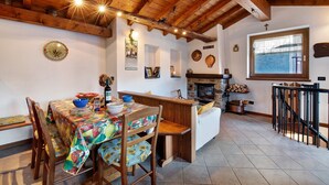 Un interior rústico con techo de madera, una mesa de comedor con sillas, chimenea y ventana con vistas.