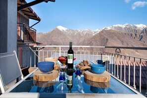 A balcony with a table set for dining, a bottle of wine, and bowls. - Holiday Home "Baita Margherita" with Mountain View & Private Terrace (Casargo)