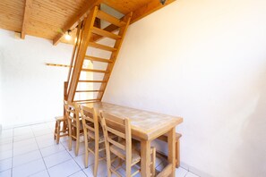 A wooden dining table with chairs, a wooden ladder, and a white wall. - Apartment No. 10 – Sleeps 8, Summer Pool, Mountain View & Shared Garden (Saint-Sorlin-d'Arves)