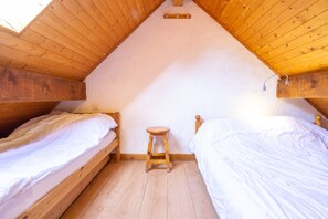 A small, cozy attic bedroom with two wooden beds, a wooden stool, and a skylight. - Apartment No. 10 – Sleeps 8, Summer Pool, Mountain View & Shared Garden (Saint-Sorlin-d'Arves)