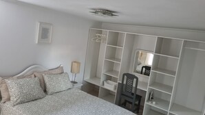 A bedroom with a bed, a desk, a chair, a wardrobe, and a mirror.