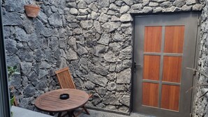 A stone wall with a wooden door and a round table with chairs.