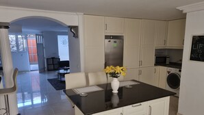 A modern kitchen with white cabinets, a black countertop, and a vase of yellow flowers.
