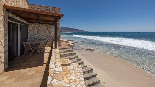 A stone building with a patio, outdoor seating, and a view of the ocean. - Vacation Home 'Casa Nostra' with Sea View, Terrace & Wi-Fi (Pájara)