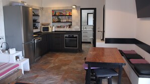 A modern kitchen with a dining area, built-in appliances, and a seating bench. - Vacation Home 'Casa Nostra' with Sea View, Terrace & Wi-Fi (Pájara)
