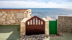 A stone wall with a wooden gate, a green door, and a view of the sea. - Vacation Home 'Casa Nostra' with Sea View, Terrace & Wi-Fi (Pájara)