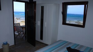 A bedroom with a bed, a wardrobe, a window with a view of the sea, and a door leading to a balcony. - Vacation Home 'Casa Nostra' with Sea View, Terrace & Wi-Fi (Pájara)