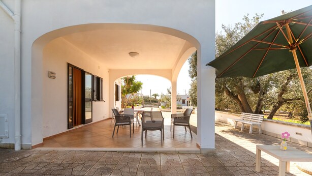 An outdoor patio with a covered seating area, a table, and a bench.
