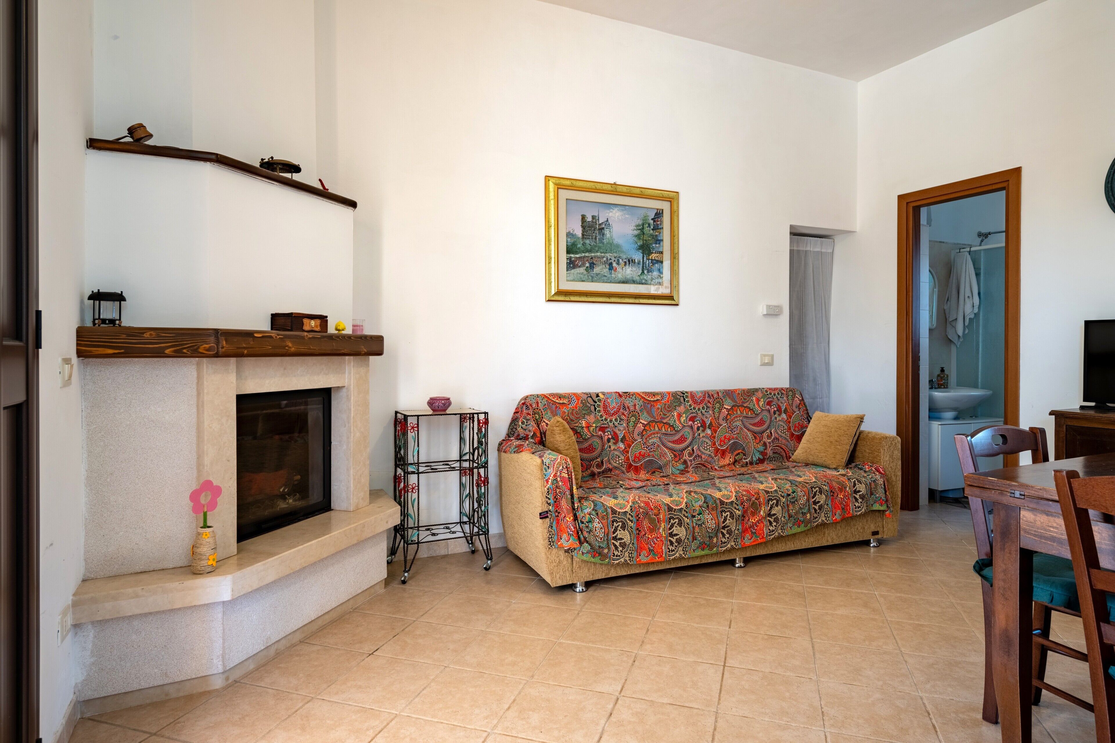 A living room with a sofa, fireplace, table, and a painting on the wall.