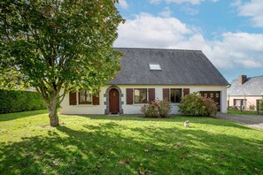 Une maison à deux étages, avec un toit en pente, une porte d’entrée et une petite fenêtre située au-dessus de la porte.