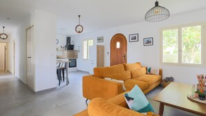 Ein modernes Wohnzimmer mit einer Couch, einem Esstisch und einer Küche im Hintergrund.