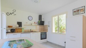 Eine moderne Küche mit weißen Schränken, einem eingebauten Backofen, einer Spüle und einem Fenster für natürliches Licht.