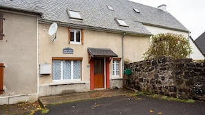A two-story building with a stone wall, a red door, and a satellite dish.