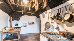 Una cocina rústica con vigas de madera, ollas colgantes y una mesa de madera con verduras.