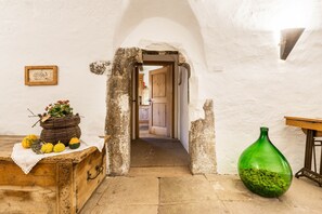 A rustic room with a wooden chest, a green glass vase, and a doorway leading to another room.
