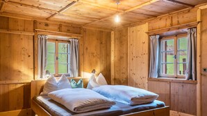 Una habitación de madera con cama, ventanas y una lámpara.