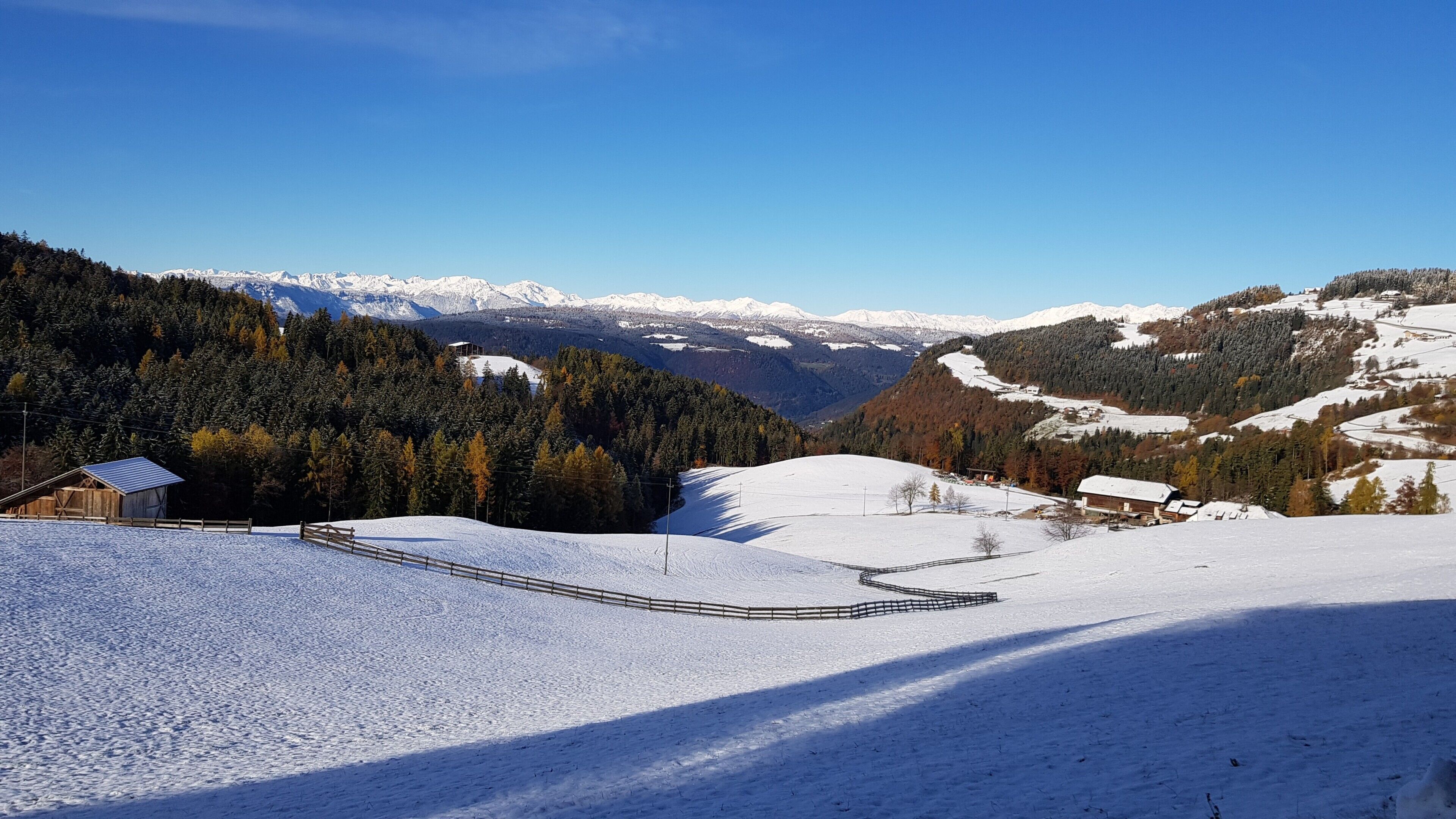 Schneebedeckte Landschaft mit einer Holzhütte und einem eingezäunten Bereich.
