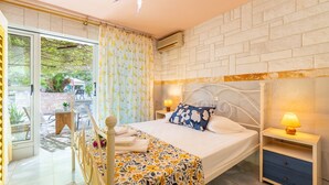 Une chambre à coucher avec un lit, des tables de chevet, un luminaire au plafond en forme d’étoile, une fenêtre avec des rideaux et une vue sur l’extérieur.