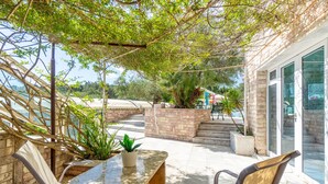 Un espace extérieur abrité, doté d’un mur en pierre, d’une plante en pot et offrant une vue sur la plage.
