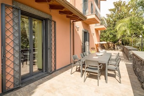 A patio with a table and chairs, a sliding glass door, and a stone wall.