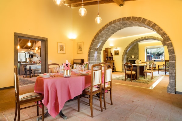 A dining area with a pink tablecloth, wooden chairs, and a stone archway.