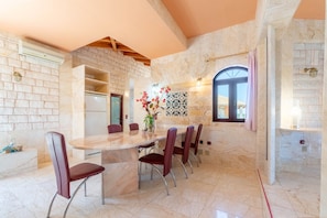 A dining area with a marble table and chairs, a vase with flowers, and a stone wall. - Country House 'Paco's Resort  Luxury Villa 31' with Sea View, Wi-Fi and Air Conditioning (Paxoi)