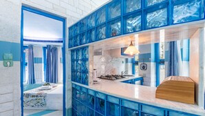 Una cocina moderna con paredes de vidrio azul, una encimera de mármol y un banco de madera.