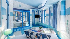 Una habitación con cama, televisión y baño con azulejos azules y ducha.