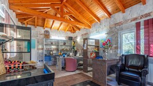 A spacious lobby with a wooden ceiling, marble walls, a reception desk, a black leather chair, and a patterned rug. - Studio Apartment 'Paco's Resort Standard  1' with Mountain View, Wi-Fi and Air Conditioning (Paxoi)